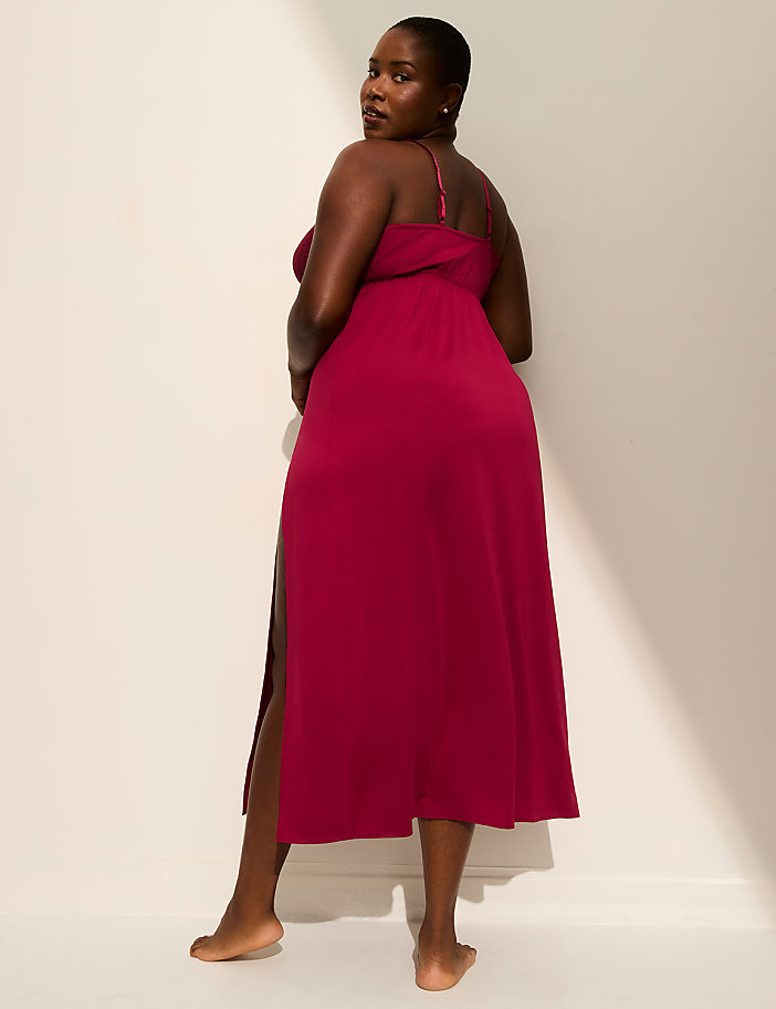 A woman in a magenta dress stands against a plain, light-colored wall with a shadow cast on it.