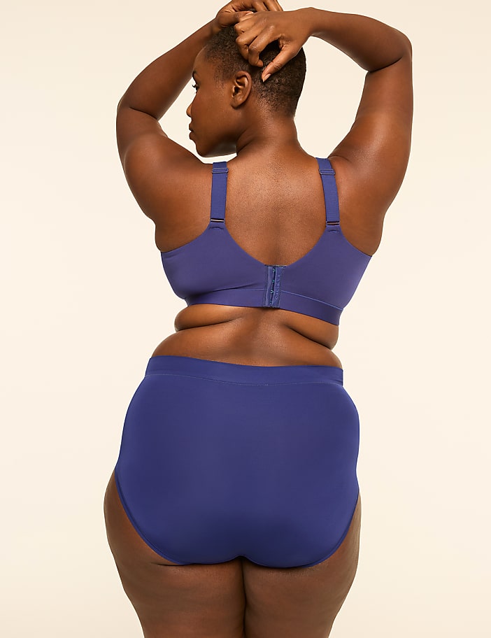 A woman in a blue bra and underwear stands with her back to the viewer against a plain, light-colored background.