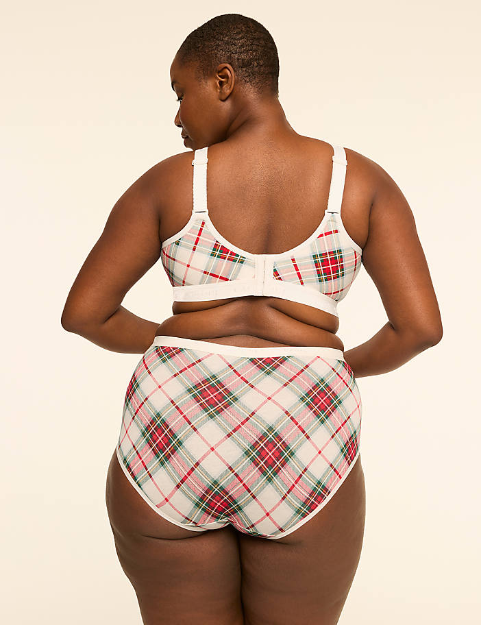 A woman in a plaid bra and underwear stands against a plain, light-colored background.