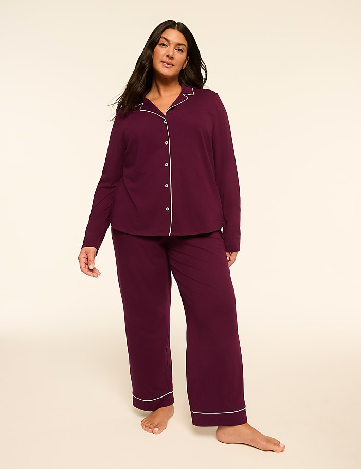 A woman in a plum-colored pajama set stands against a plain, light background.