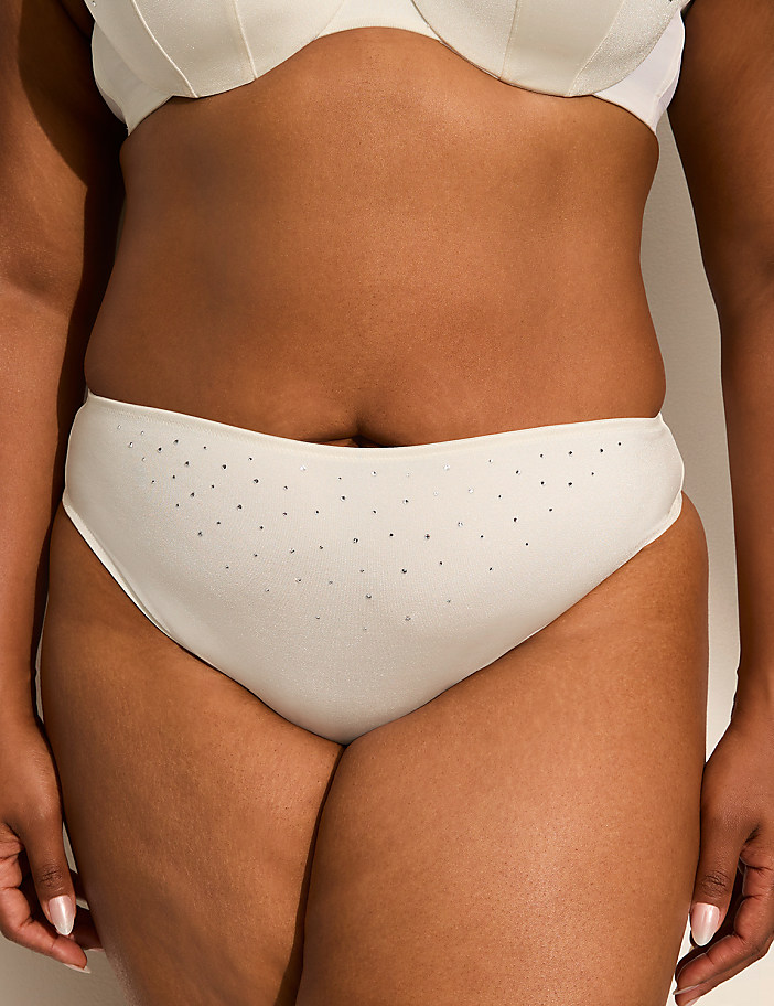 A person's midsection is shown in the foreground, wearing white underwear with small dots, against a plain white background.