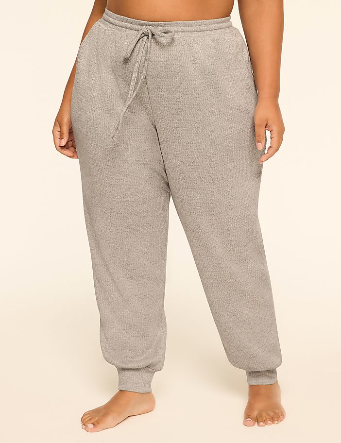 A person wearing grey sweatpants with a drawstring stands against a plain, light-colored background.