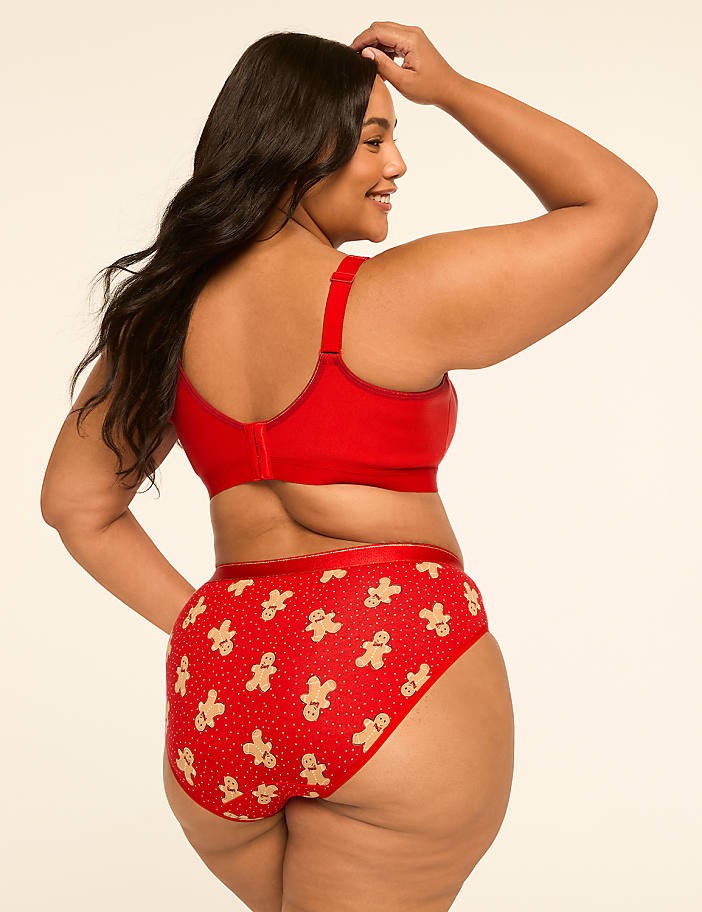 A woman in red gingerbread-patterned underwear and a matching bra poses against a plain, light background.