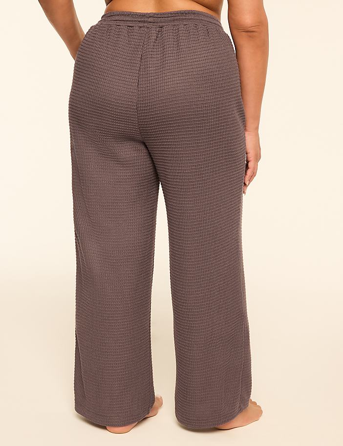 A person stands in the foreground wearing waffle-knit gray pants against a plain, light-colored background.