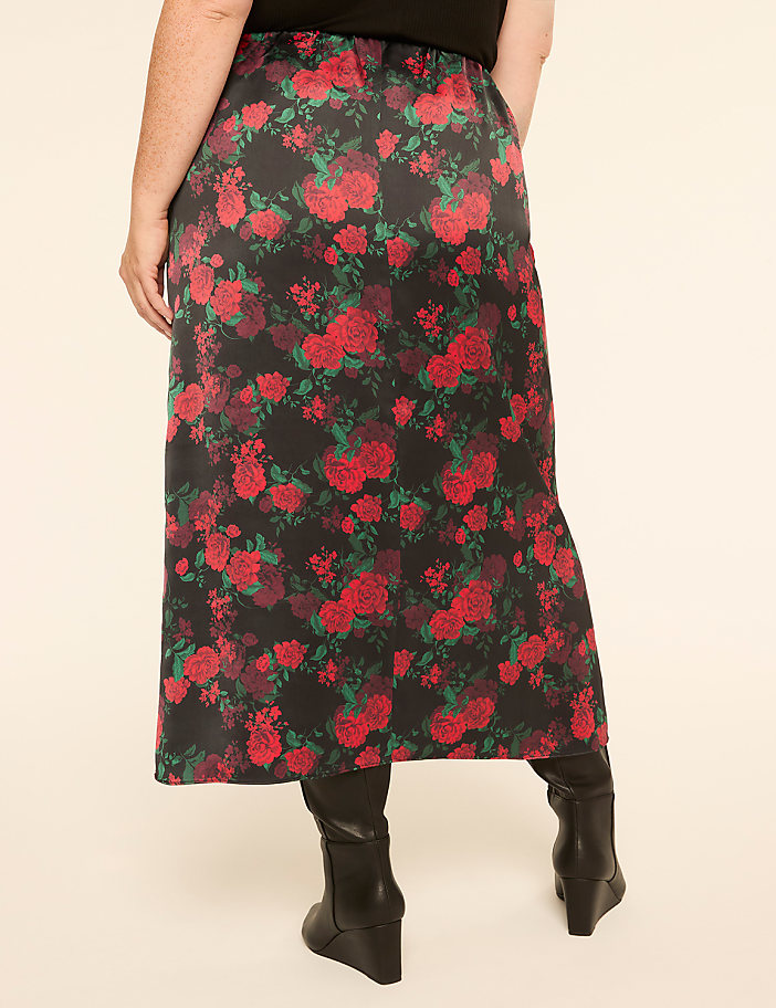 A person wearing a floral skirt and black boots stands against a plain, light-colored background.
