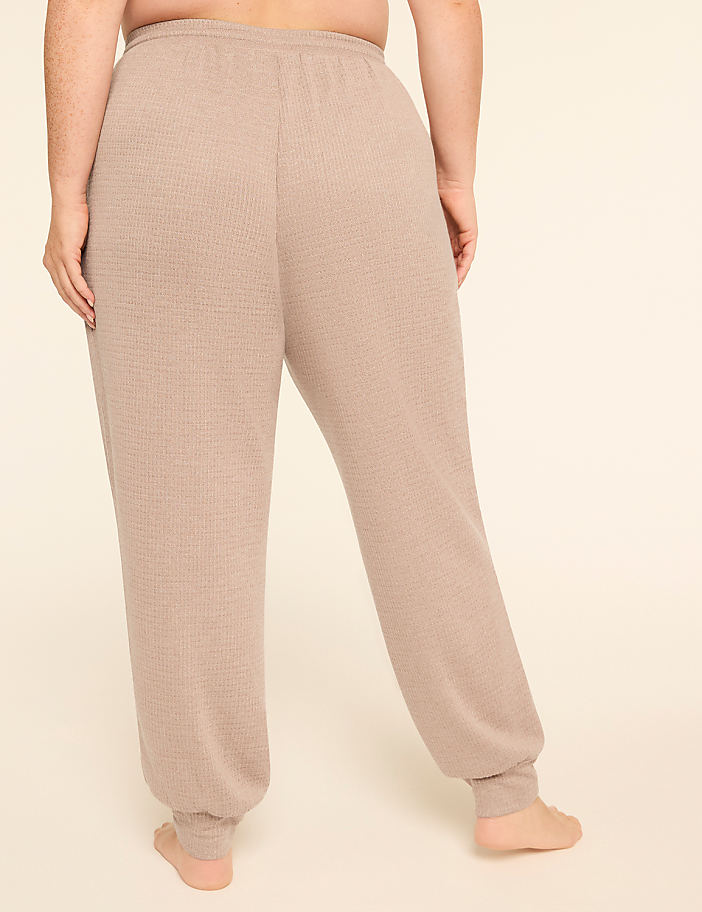 A person wearing beige waffle-knit sweatpants stands against a plain, light-colored background.