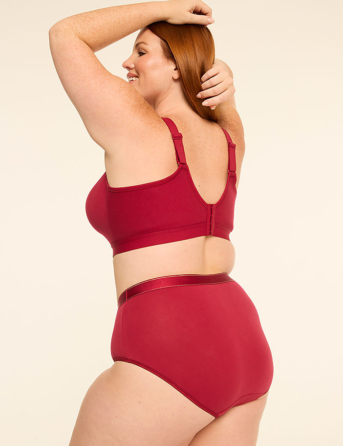 A woman in a red bra and high-waisted underwear poses against a plain, light-colored background.