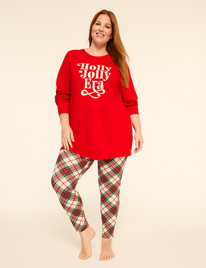 A woman in a red "Holly Jolly Era" sweater and plaid leggings stands against a plain, light background.