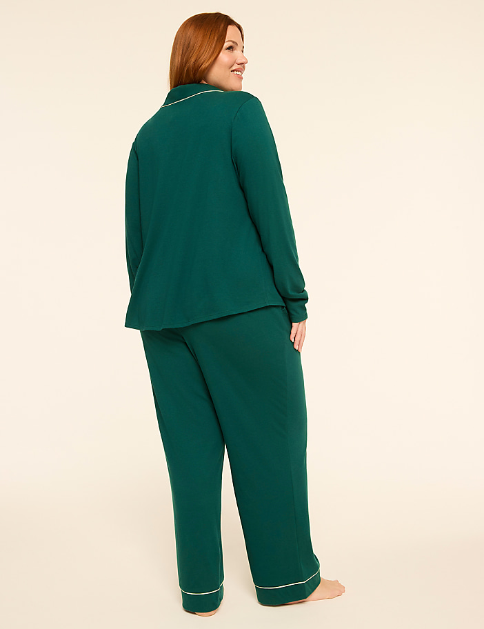 A woman in a green pajama set stands against a plain, light-colored background.