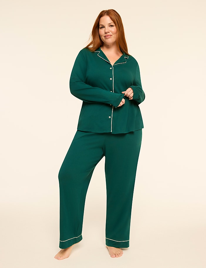 A woman in a green pajama set stands against a plain, light-colored background.