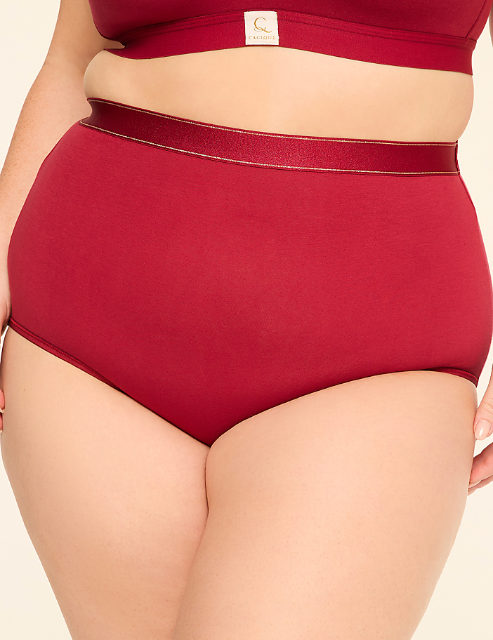A person in maroon high-waisted underwear and a matching bra stands against a plain, light background.