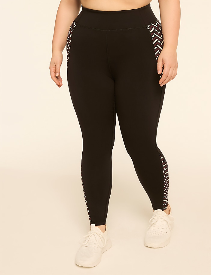 A person wearing black leggings with a geometric pattern on the sides stands against a plain, light-colored background.