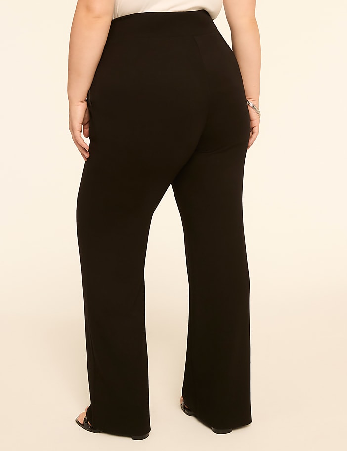 A person wearing black wide-leg pants stands against a plain, light-colored background.