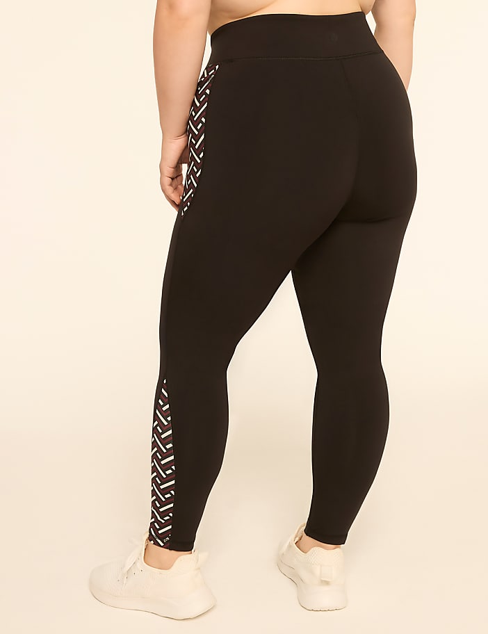A person wearing black leggings with a geometric pattern on the side stands against a plain, light-colored background.