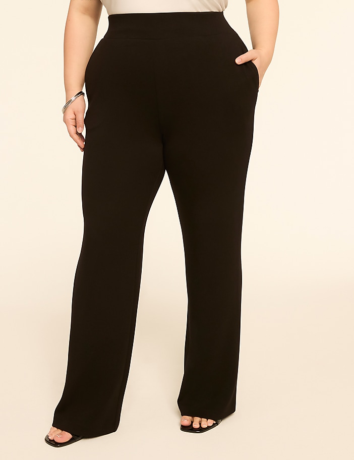 A person in black flared pants stands against a plain, light-colored background.