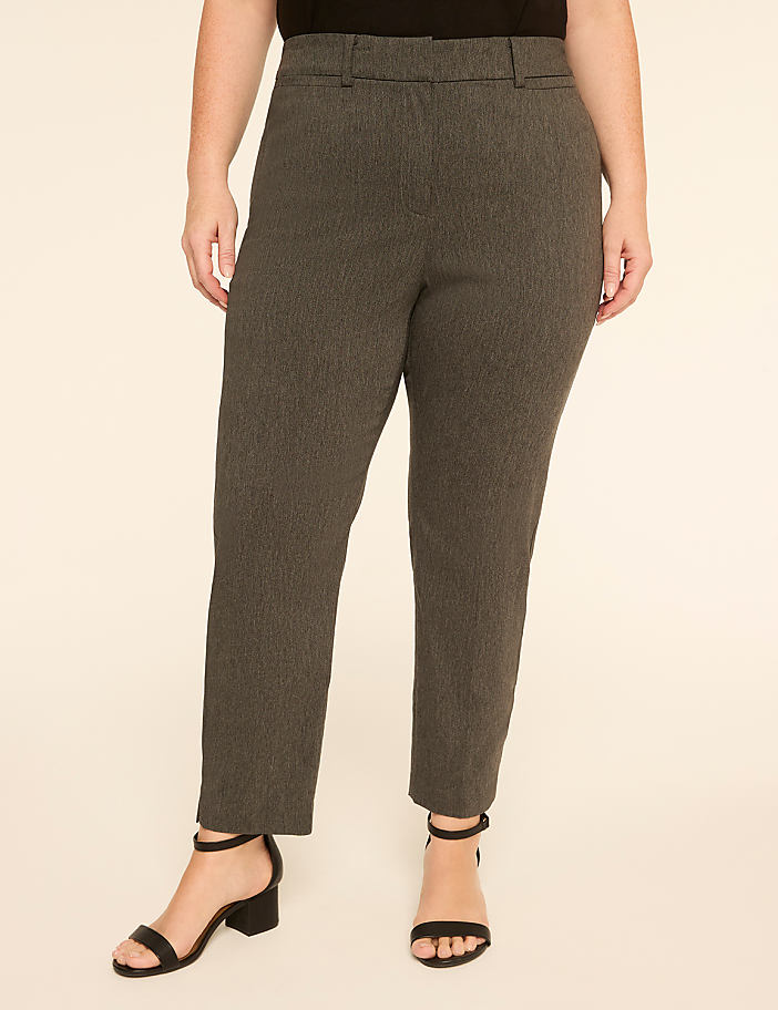 A woman stands in gray pinstripe pants and black heels against a plain cream background.