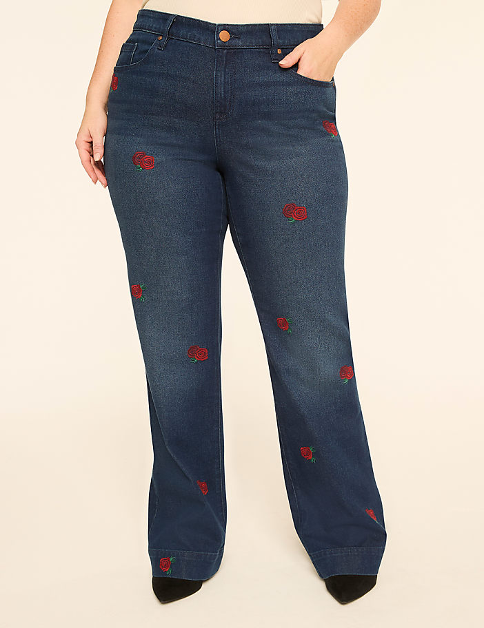 Dark wash denim jeans with embroidered red roses are displayed against a plain, light-colored background.