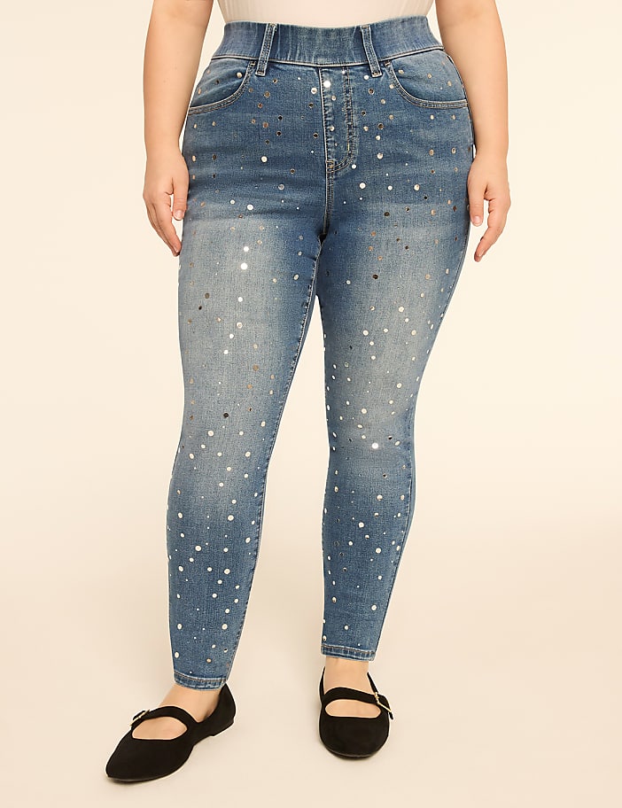 A person wearing sparkly blue jeans and black flats stands against a plain, light-colored background.
