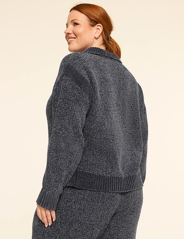 A woman in a dark blue chenille sweater and matching pants stands against a plain, light-colored background.