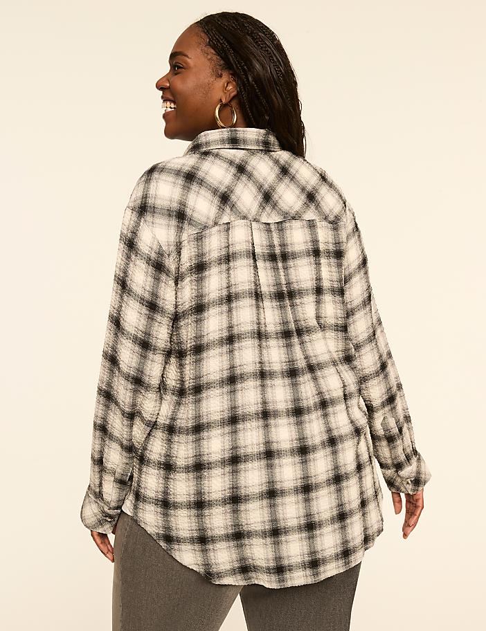 A woman in a plaid shirt is shown from the back against a plain, light-colored background.