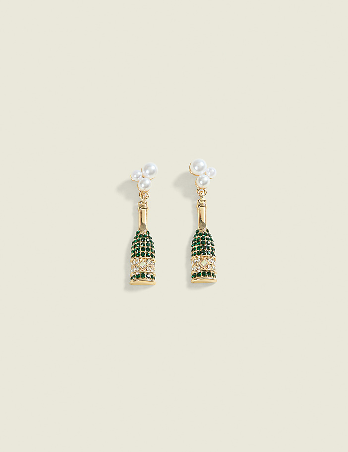 A pair of champagne bottle-shaped earrings with pearl accents dangle against a pale cream background.