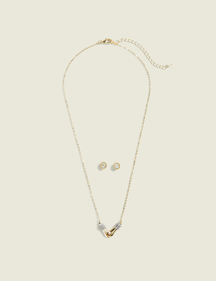 A gold necklace with a pendant and matching stud earrings are laid out on a plain, light-colored background.
