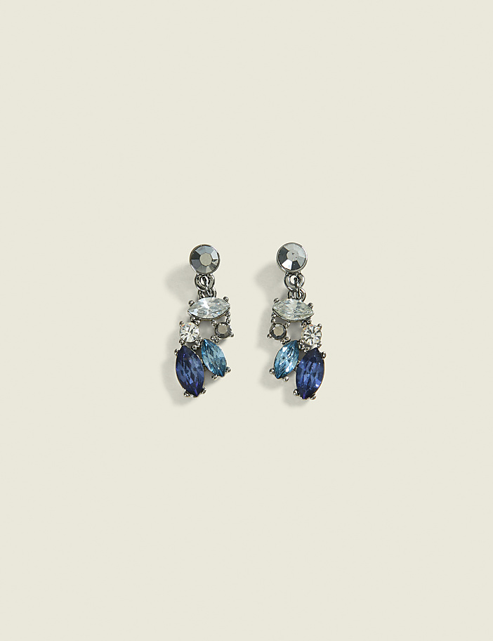 A pair of dangling earrings with blue and clear crystals are set against a plain, light-colored background.