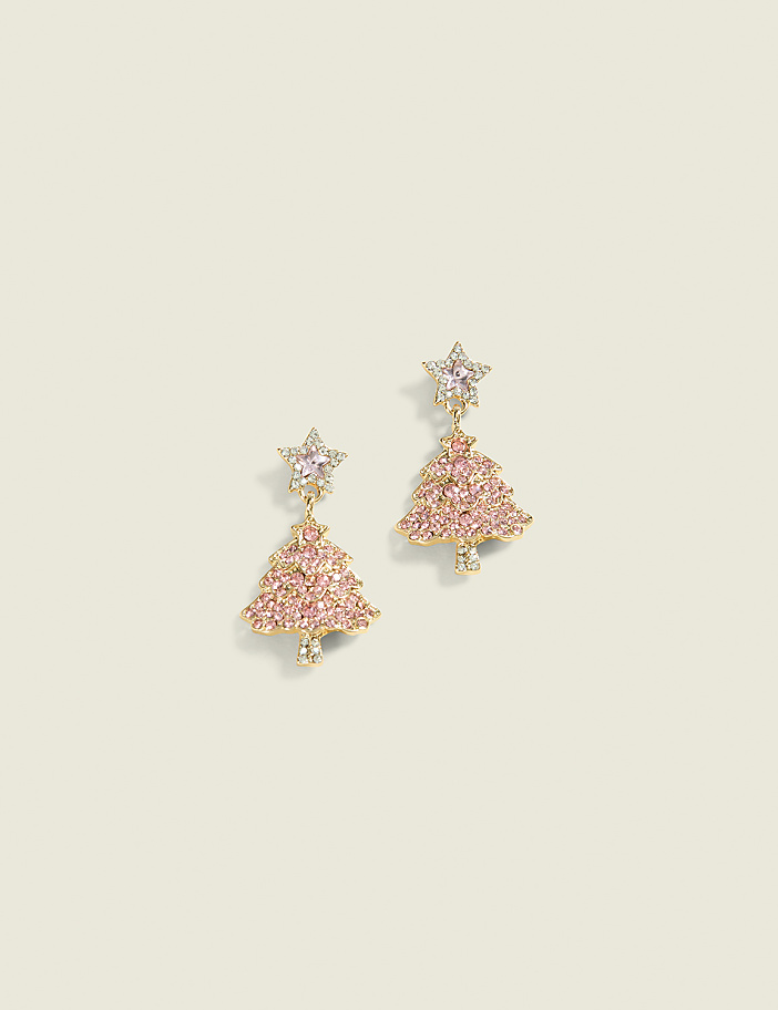 A pair of pink Christmas tree-shaped earrings with star toppers dangle against a plain, light-colored background.
