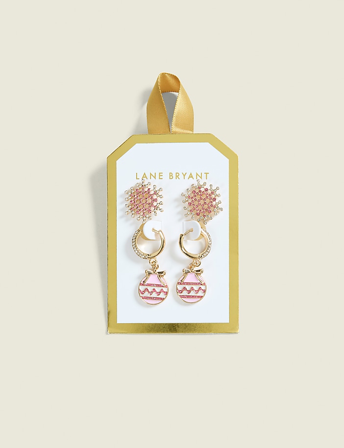 Two pairs of pink and gold earrings, one with a snowflake design and the other with ornament-shaped drops, are displayed on a white and gold card against a pale yellow background.