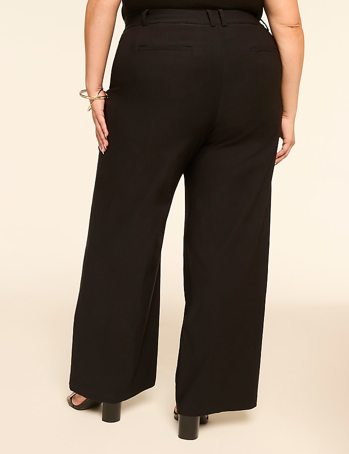 A person wearing black wide-leg pants stands against a plain, light-colored background.