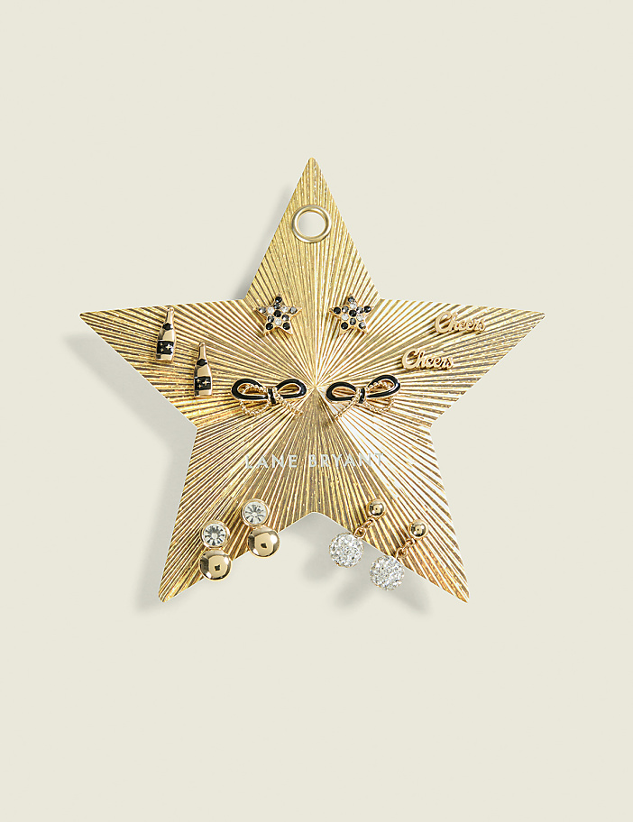 A gold star-shaped jewelry holder with various earrings is displayed against a plain, light-colored background.