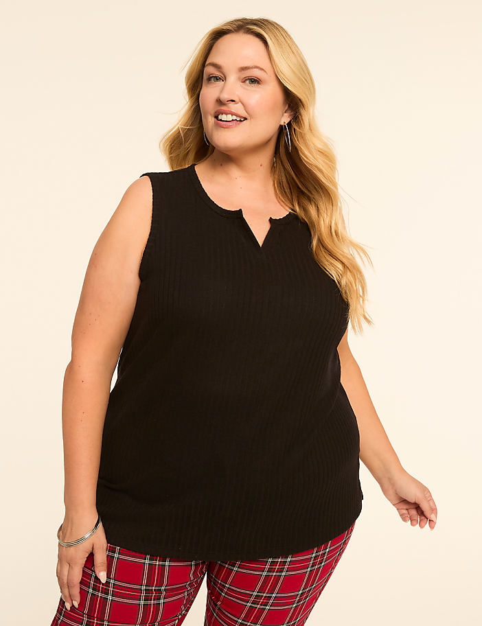 A woman in a black sleeveless top and red plaid pants smiles against a plain, light-colored background.