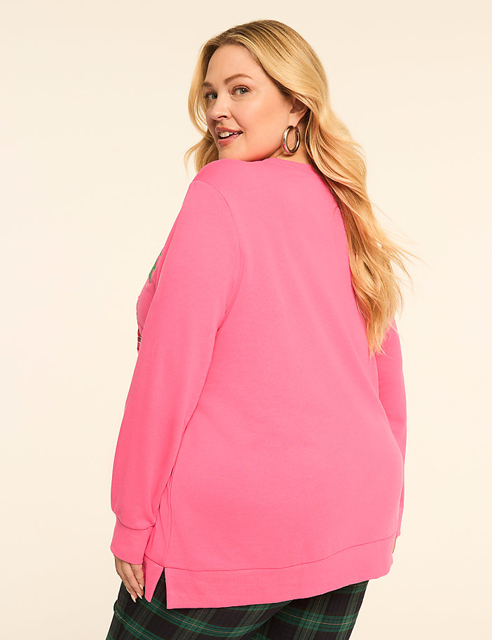 A woman in a bright pink sweatshirt and plaid pants stands against a plain, light-colored background.