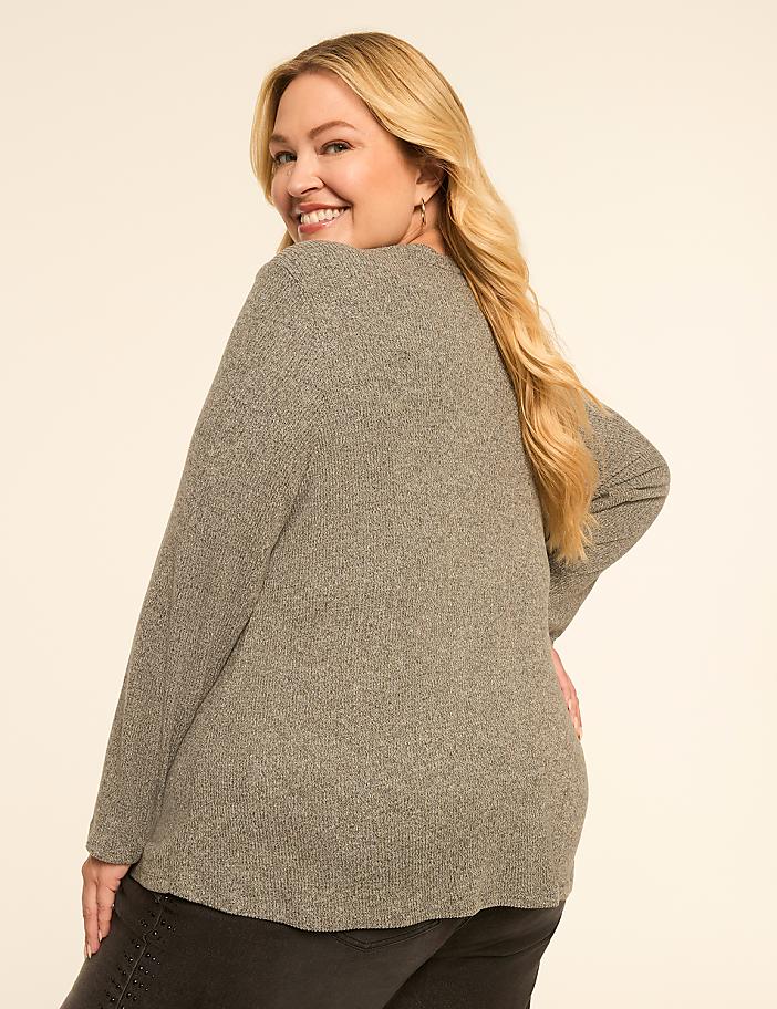 A smiling woman in a gray sweater poses against a plain, light-colored background.