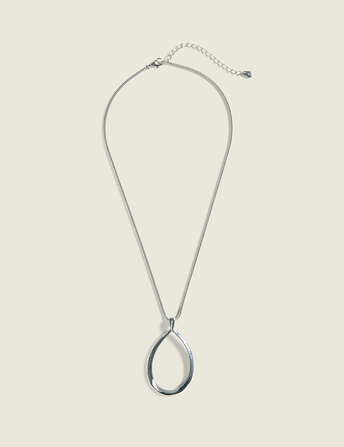 A silver teardrop pendant hangs from a delicate chain against a plain, light beige background.
