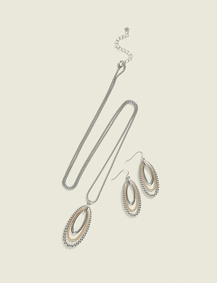 A silver necklace with an oval pendant and matching oval drop earrings are laid out on a plain, light beige background.