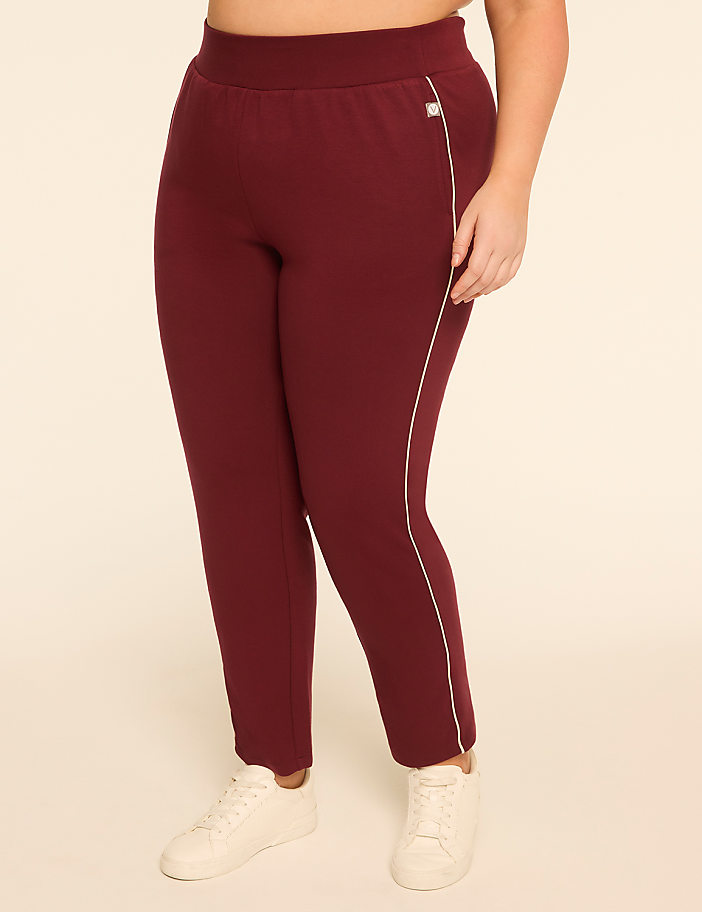 A person wearing maroon sweatpants with a white stripe down the side stands against a plain, light-colored background.
