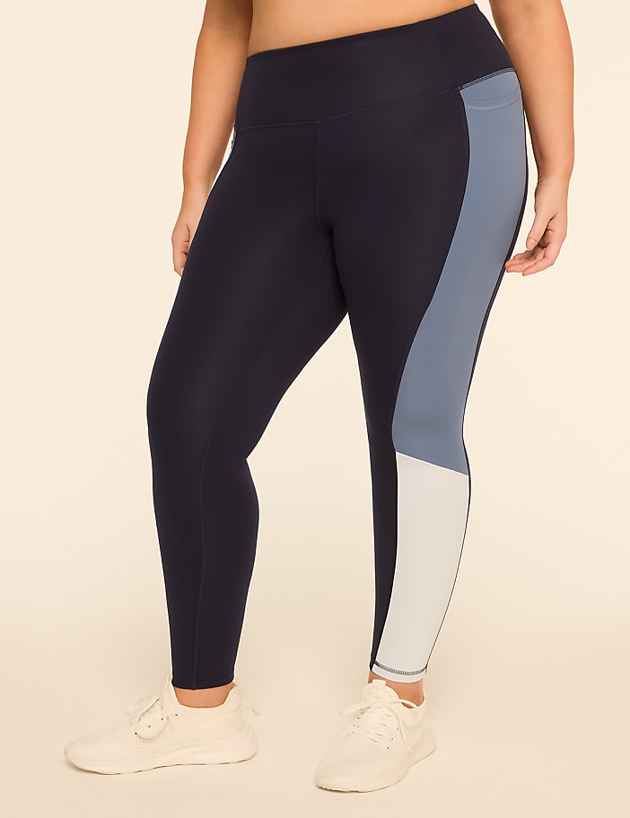 A person wearing navy blue leggings with light blue and white color blocking stands against a plain, light-colored background.