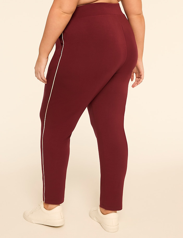 A person wearing maroon pants with a white stripe down the side stands against a plain, light-colored background.