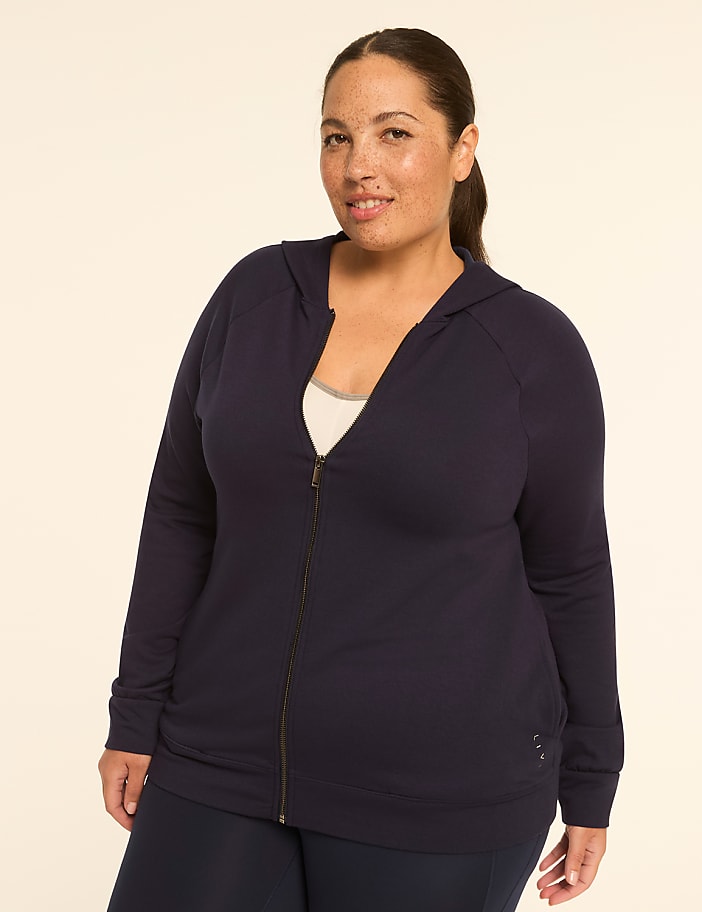 A plus-size woman in a navy blue zip-up hoodie stands against a plain, light-colored background.