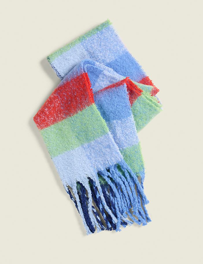 A fuzzy, striped scarf with blue fringe lies on a plain, light-colored background.