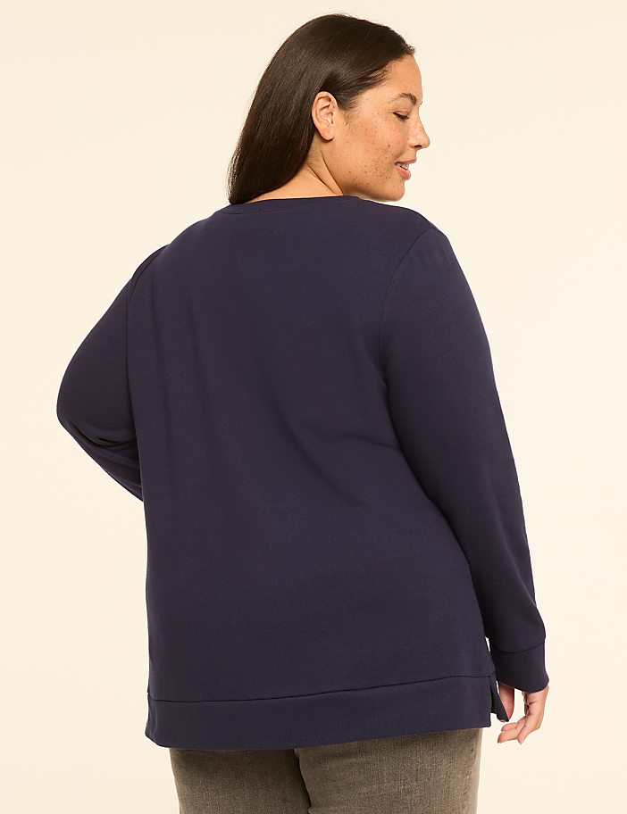 A woman in a navy sweatshirt stands against a plain, light-colored background.