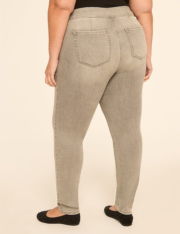 A person wearing grey jeggings and black flats stands against a plain beige background.
