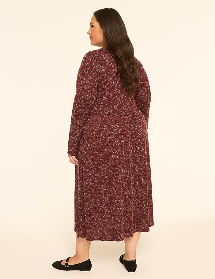 A woman in a maroon speckled dress stands against a plain, light-colored background.