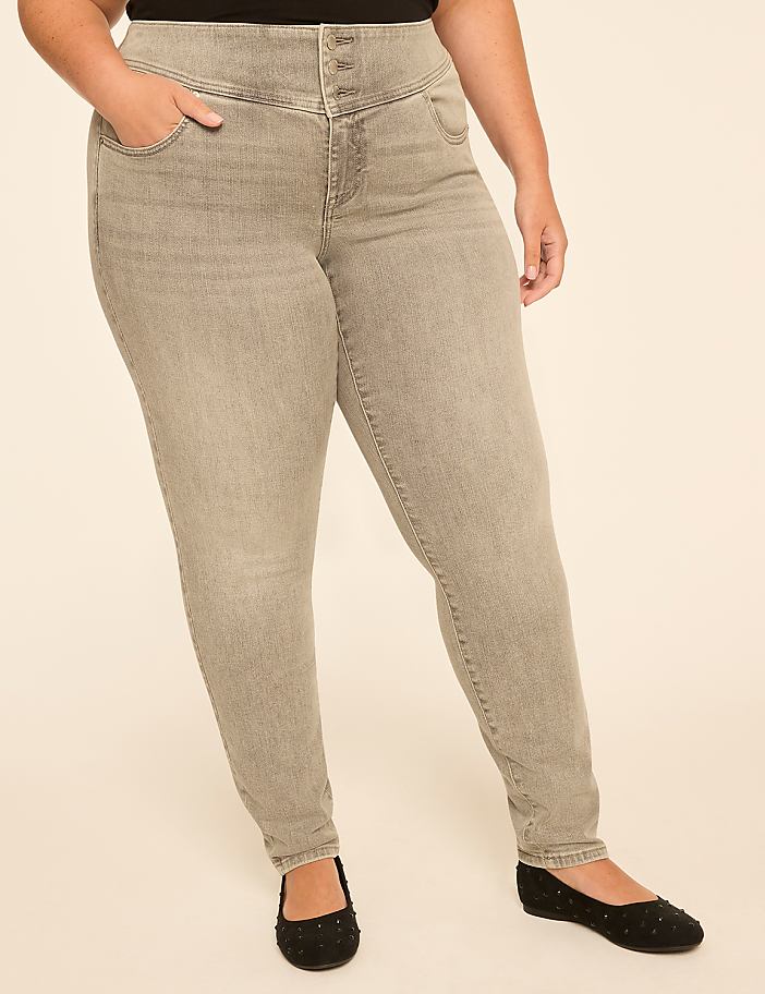 A person wearing high-waisted grey jeans and black ballet flats stands against a plain, light-colored background.