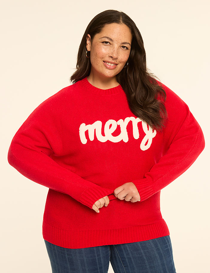 A woman in a red "merry" sweater stands against a plain, light-colored background.