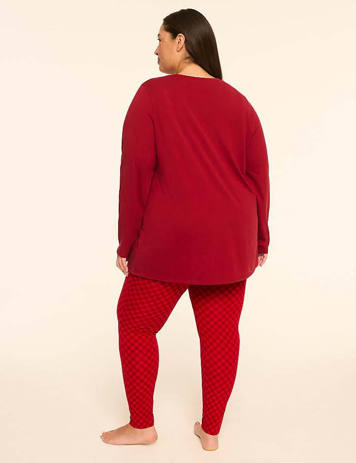 A woman in a red long-sleeved shirt and patterned red leggings stands barefoot against a plain, light-colored background.
