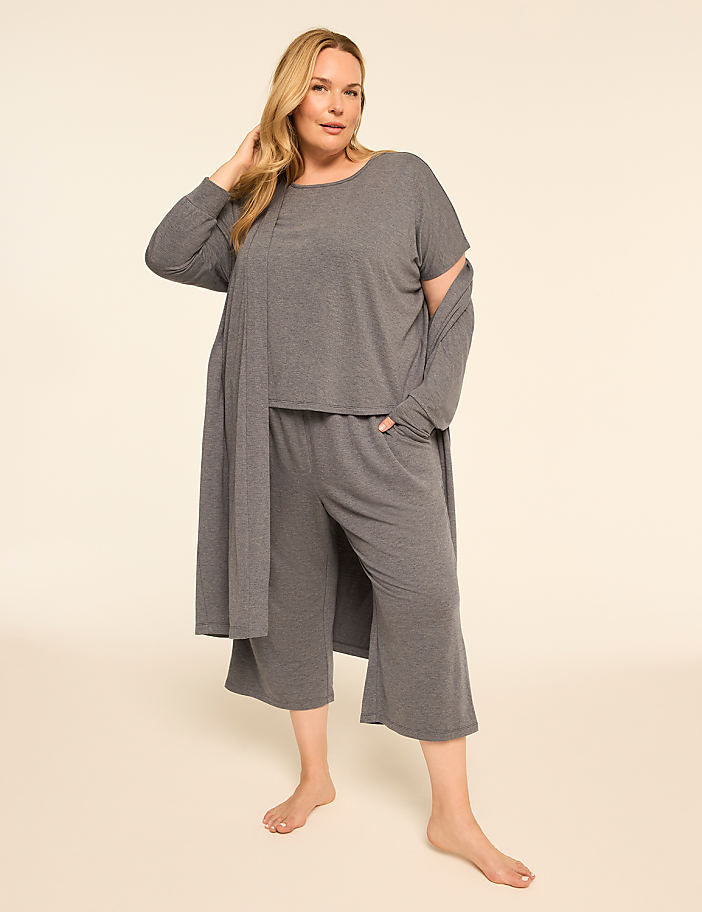 A woman in a grey loungewear set stands against a plain, light-colored background.