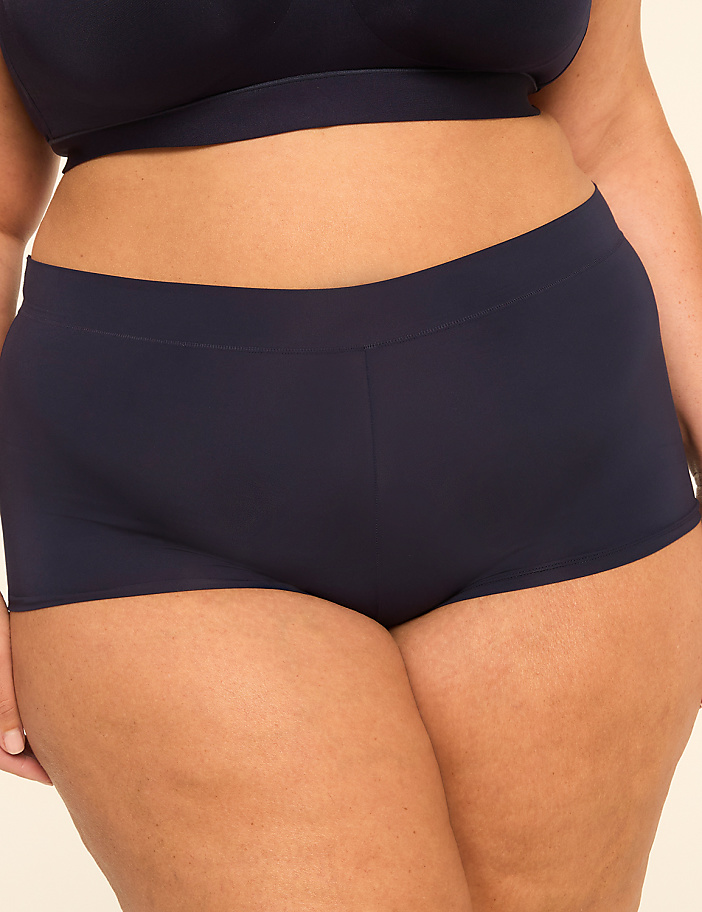 A woman in navy blue underwear stands against a plain, light-colored background.