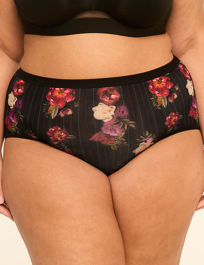 A person wears floral patterned underwear with a black bra in the background.